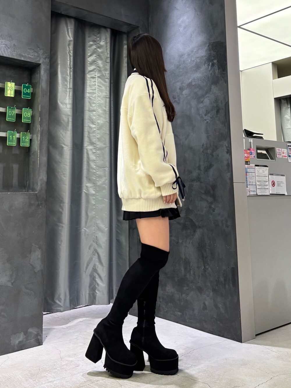 ホワイト系のブルゾン、ブラック系のスカート、ブラック系のブーツを着用したレディースの秋コーディネートの2枚目の写真