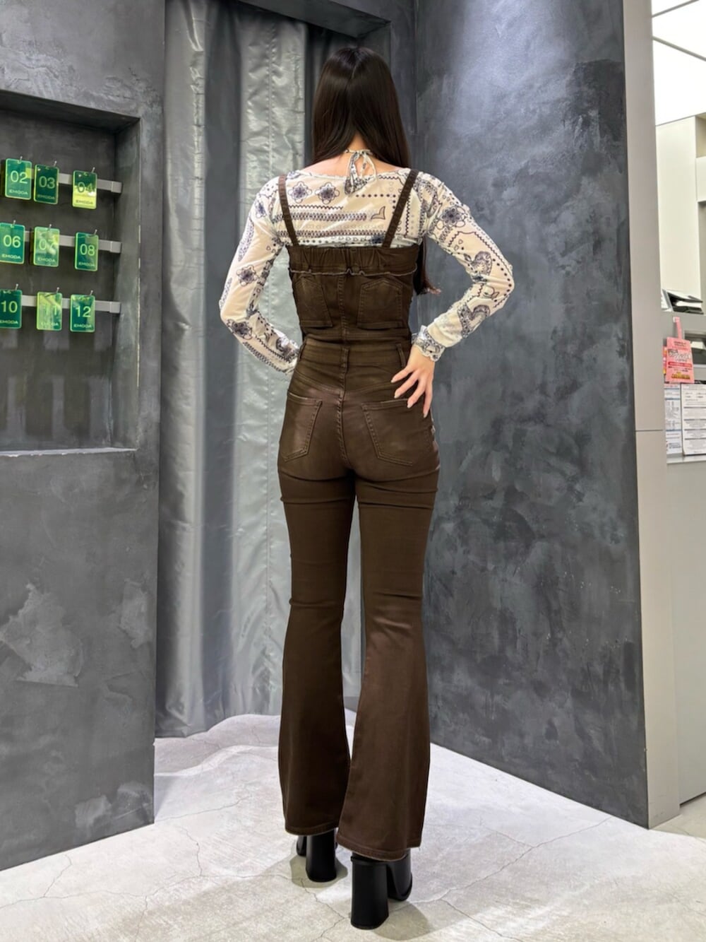 ブラウン系のサロペット/オーバーオール、ホワイト系のTシャツ/カットソー、ブラック系のサンダルを着用したレディースの春コーディネートの3枚目の写真