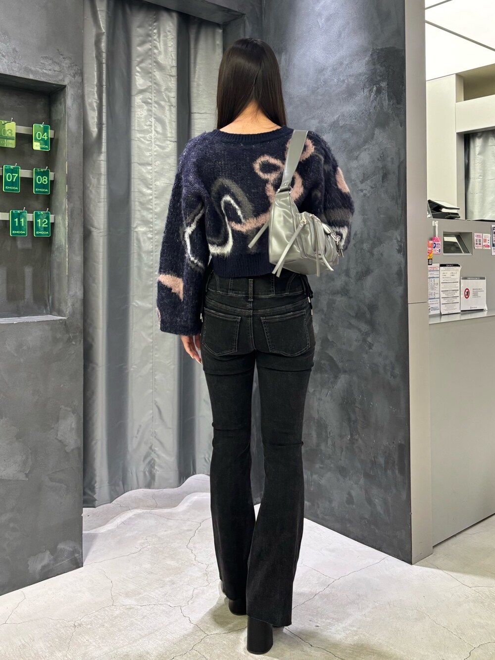 ブルー系のニット/セーター、グレー系のハンドバッグ、ブラック系のデニムパンツを着用したレディースの秋コーディネートの3枚目の写真