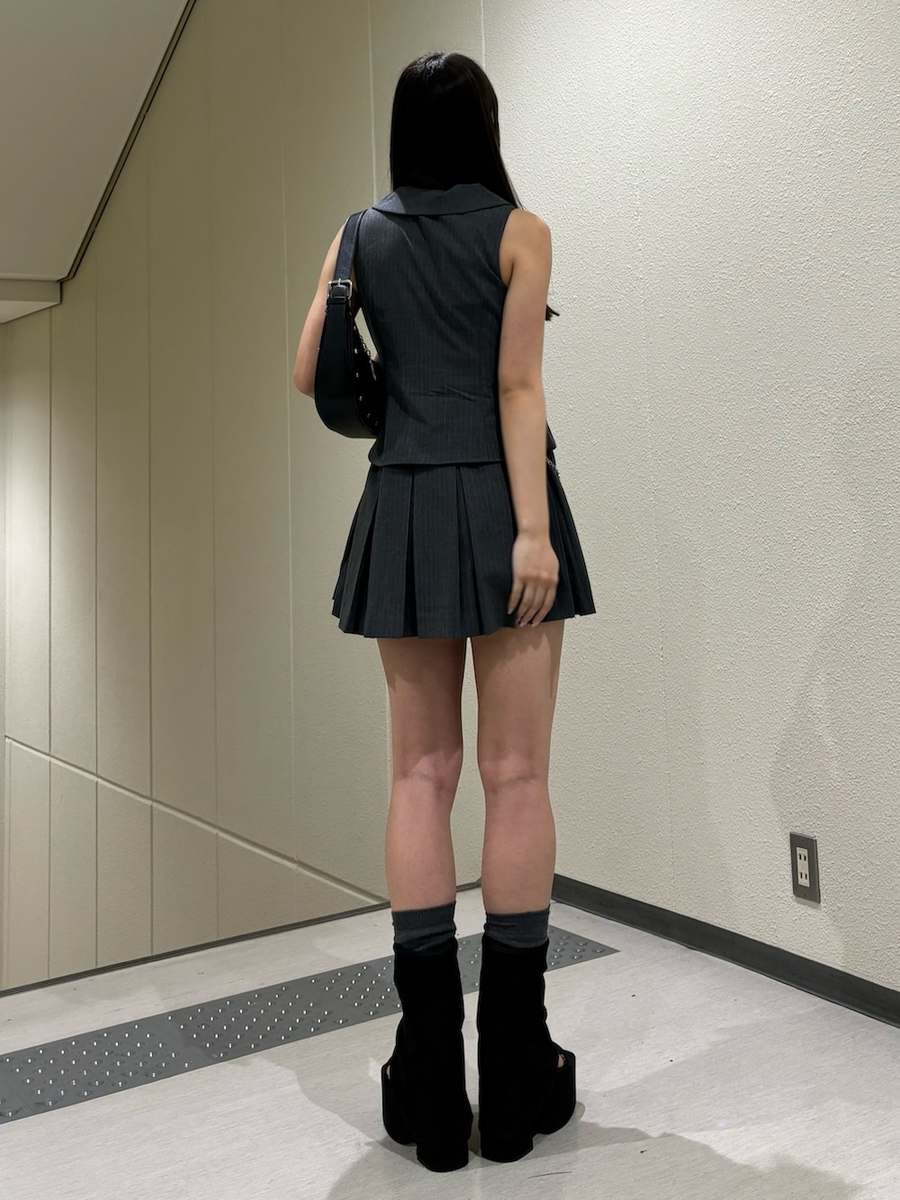 ブラック系のサンダル、ブラック系のハンドバッグ、グレー系のワンピースを着用したレディースの春コーディネートの3枚目の写真