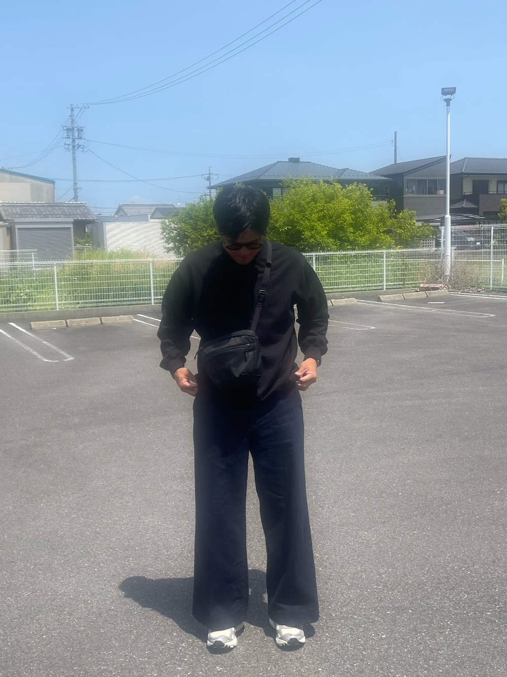 ブルー系のデニムパンツ、ブラック系のボディバッグ/ウエストポーチ、ブラック系のスウェットを着用したメンズの春コーディネートの3枚目の写真