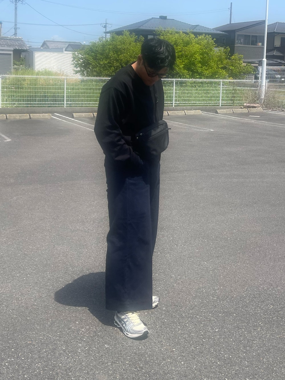 ブルー系のデニムパンツ、ブラック系のボディバッグ/ウエストポーチ、ブラック系のスウェットを着用したメンズの春コーディネートの2枚目の写真