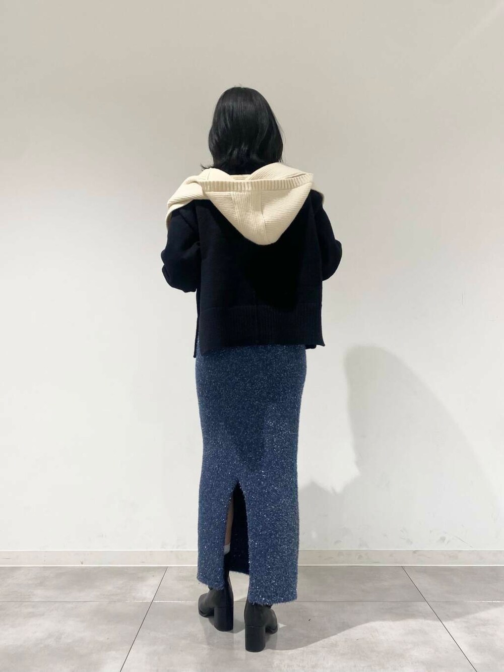 ブラック系のブーツ、ブルー系のスカート、ブラック系のニット/セーターを着用したレディースの冬コーディネートの2枚目の写真