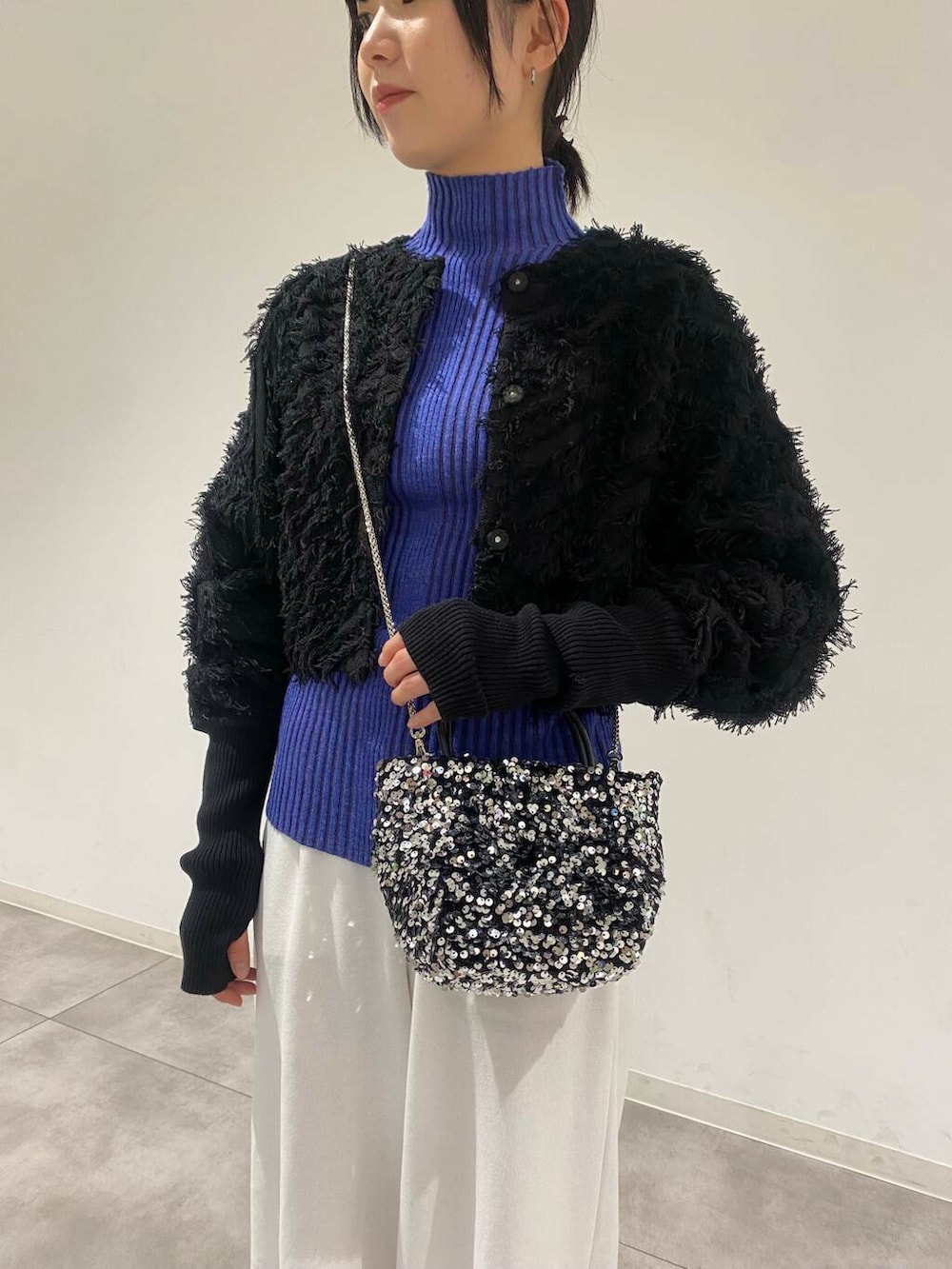 シルバー系のショルダーバッグ、グレー系のダウンジャケット/コート、ブルー系のニット/セーターを着用したレディースの冬コーディネートの2枚目の写真