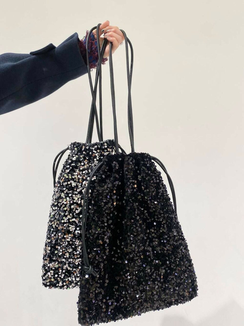 ブルー系のステンカラーコート、ブルー系のニット/セーター、シルバー系のブーツを着用したレディースの冬コーディネートの2枚目の写真