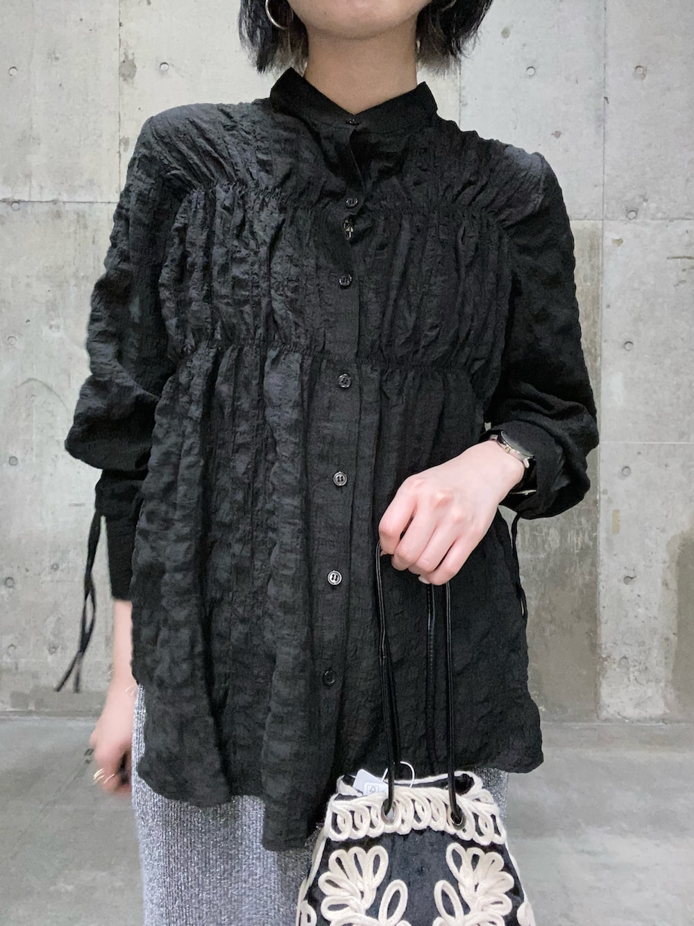 ブラック系のシャツ/ブラウス、グレー系のスカート、ブラウン系のハンドバッグを着用したレディースの夏コーディネートの2枚目の写真