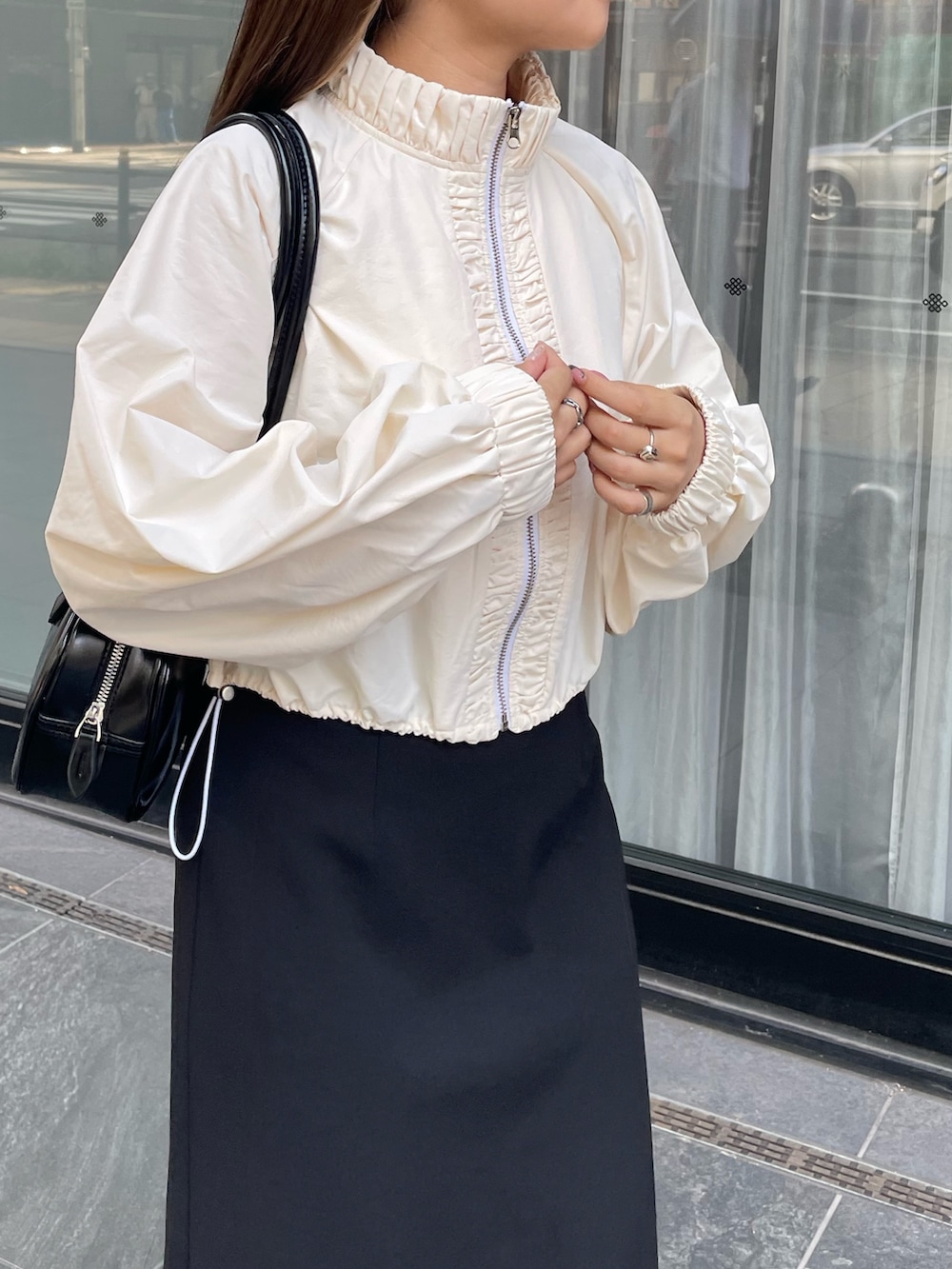 ホワイト系のナイロンジャケット、グレー系のスニーカー、ブラック系のショルダーバッグを着用したレディースの夏コーディネートの4枚目の写真