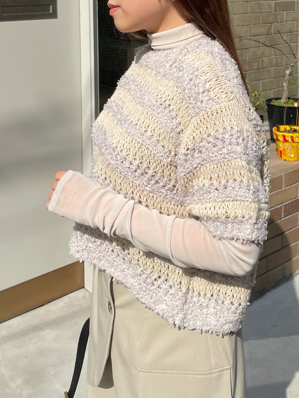 グレー系のニット/セーター、ベージュ系のその他パンツ、ブラック系のショルダーバッグを着用したレディースの春コーディネートの2枚目の写真