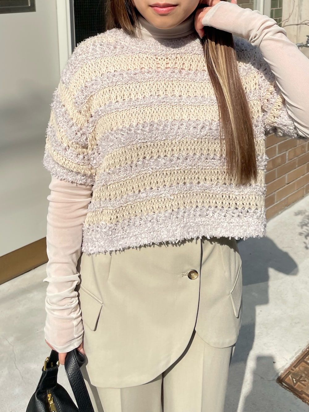 グレー系のニット/セーター、ベージュ系のその他パンツ、ブラック系のショルダーバッグを着用したレディースの春コーディネートの3枚目の写真