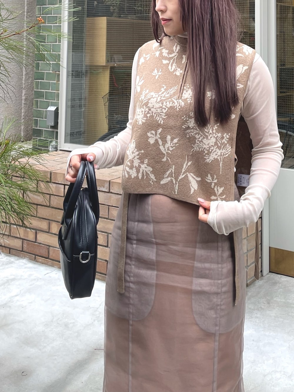 ベージュ系のベスト、ベージュ系のスカート、ブラック系のブーツを着用したレディースの春コーディネートの3枚目の写真