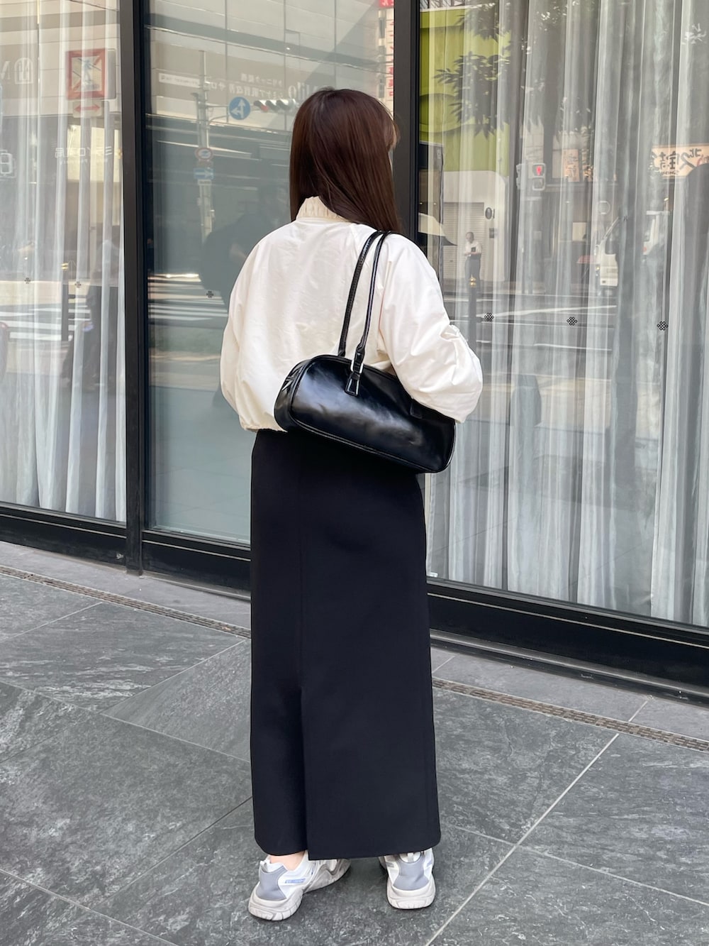 ホワイト系のナイロンジャケット、グレー系のスニーカー、ブラック系のショルダーバッグを着用したレディースの夏コーディネートの3枚目の写真