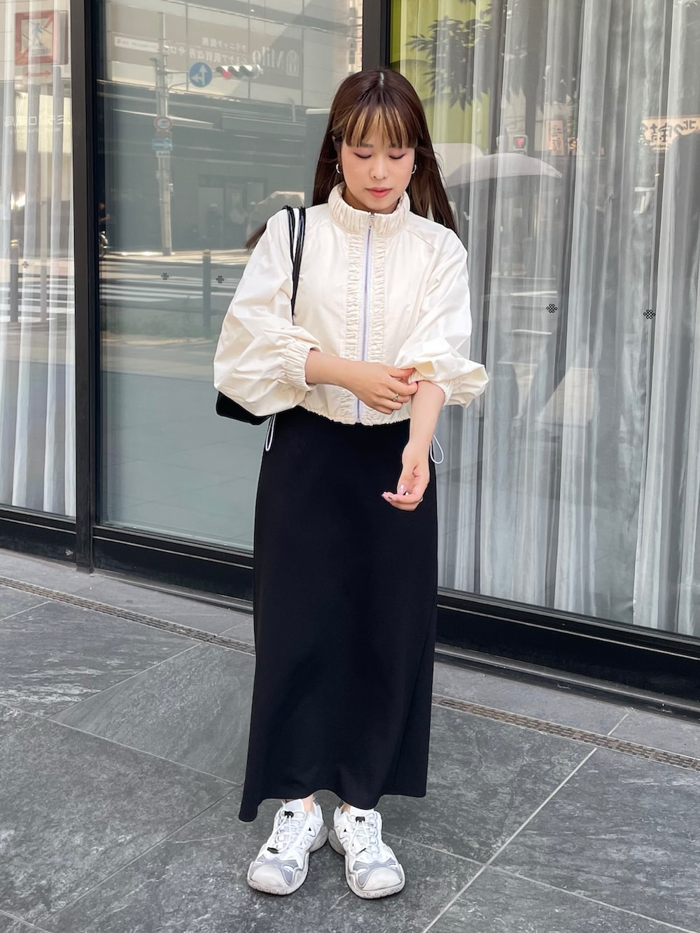 ホワイト系のナイロンジャケット、グレー系のスニーカー、ブラック系のショルダーバッグを着用したレディースの夏コーディネートの2枚目の写真