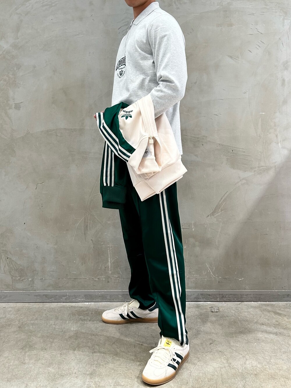 グレー系のポロシャツ、ホワイト系のトップス、グリーン系のスウェットパンツを着用したメンズの春コーディネートの3枚目の写真