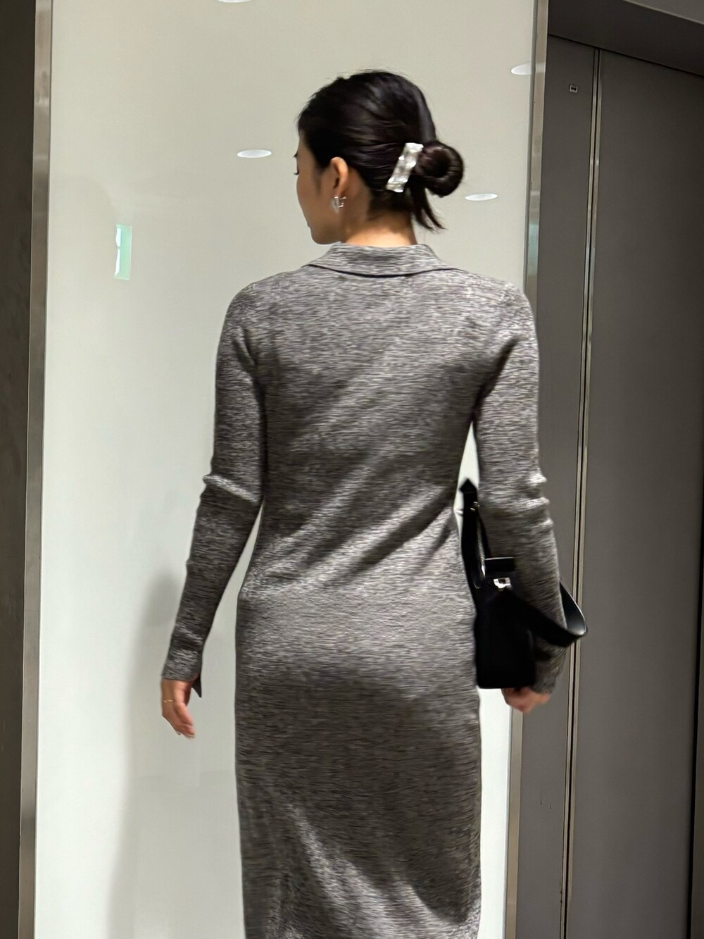 グレー系のワンピース、ブラック系のパンプス、ブラック系のハンドバッグを着用したレディースの冬コーディネートの3枚目の写真