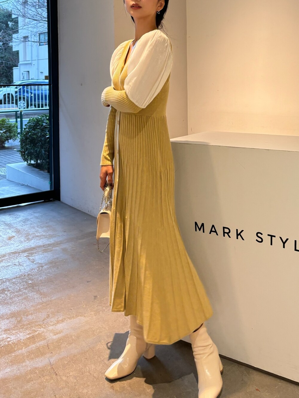 イエロー系のワンピース、ホワイト系のブーツを着用したレディースの冬コーディネートの3枚目の写真