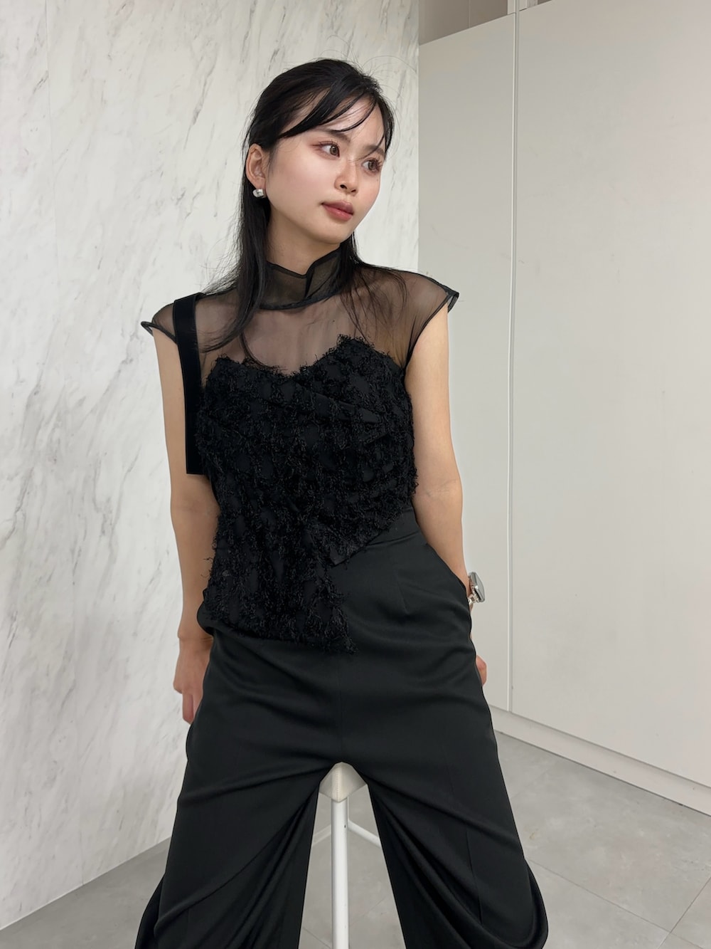 ブラック系のパンツドレス、ブラック系のハンドバッグ、シルバー系のパンプスを着用したレディースの冬コーディネートの2枚目の写真