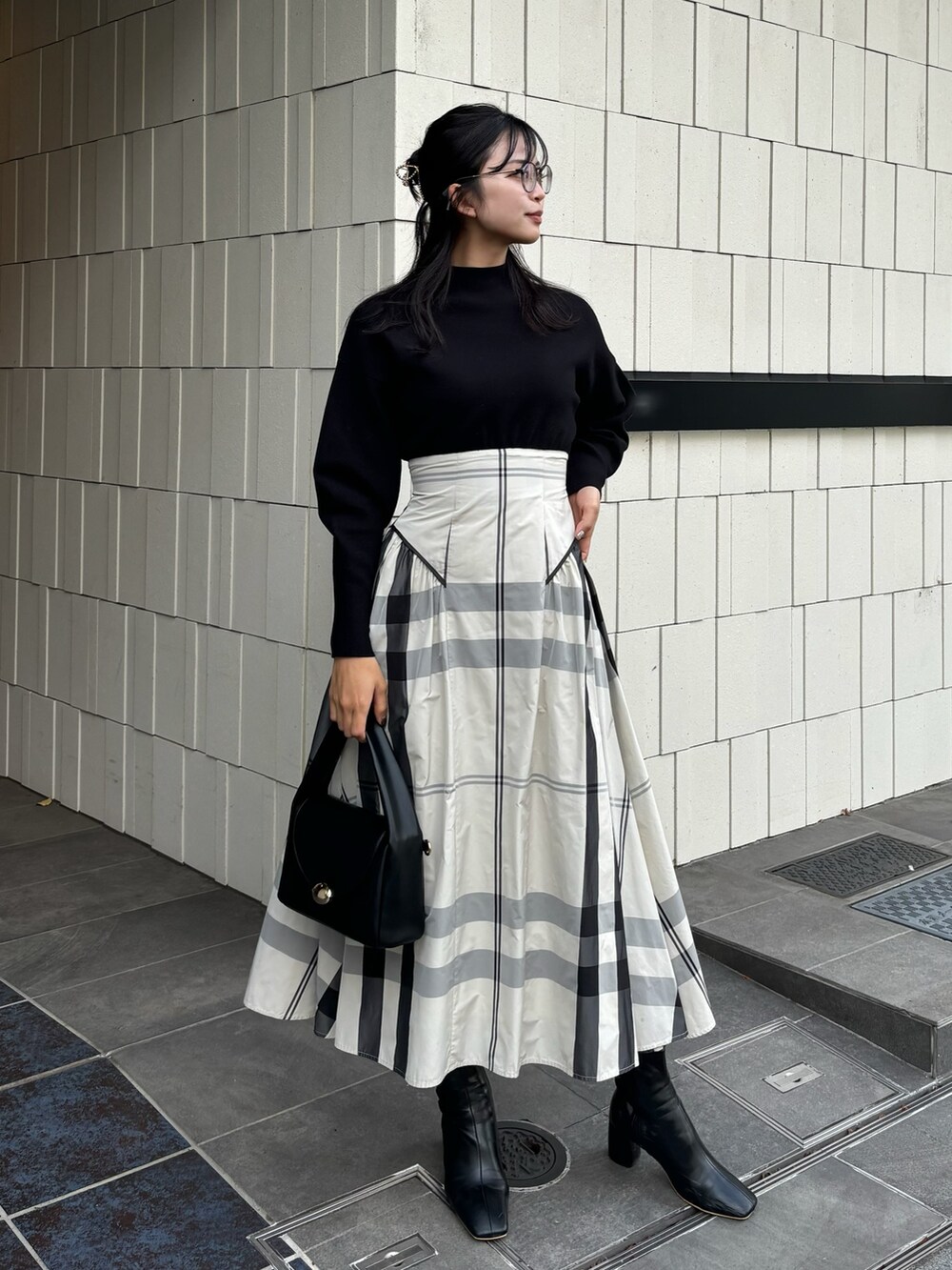 ホワイト系のワンピース、ブラック系のハンドバッグ、ブラック系のブーツを着用したレディースの冬コーディネートの2枚目の写真