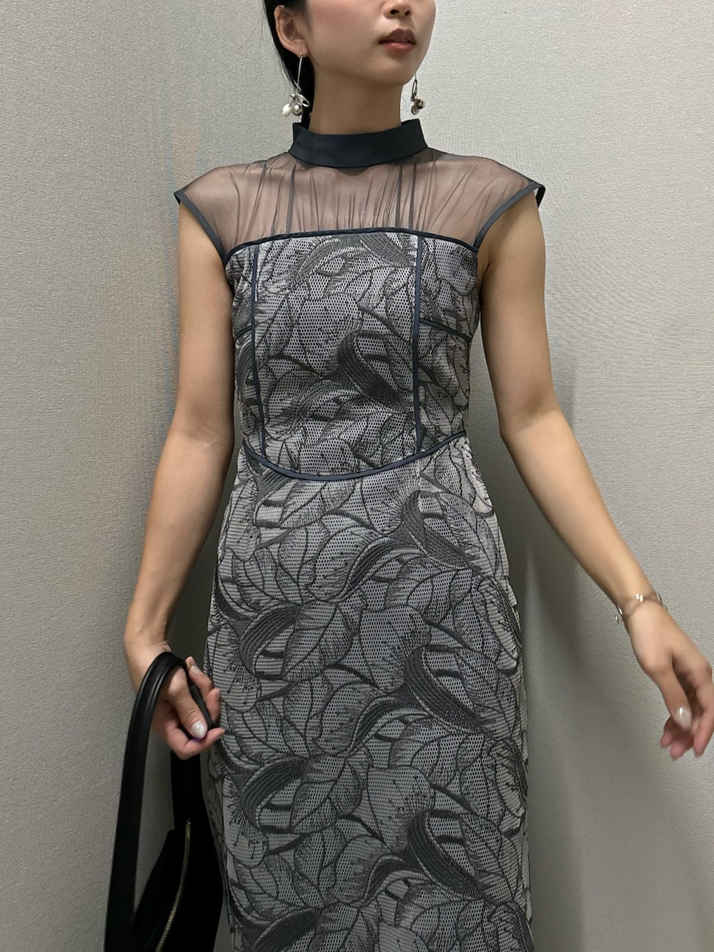 ブルー系のドレス、ブラック系のハンドバッグ、シルバー系のピアス（両耳用）を着用したレディースの春コーディネートの4枚目の写真