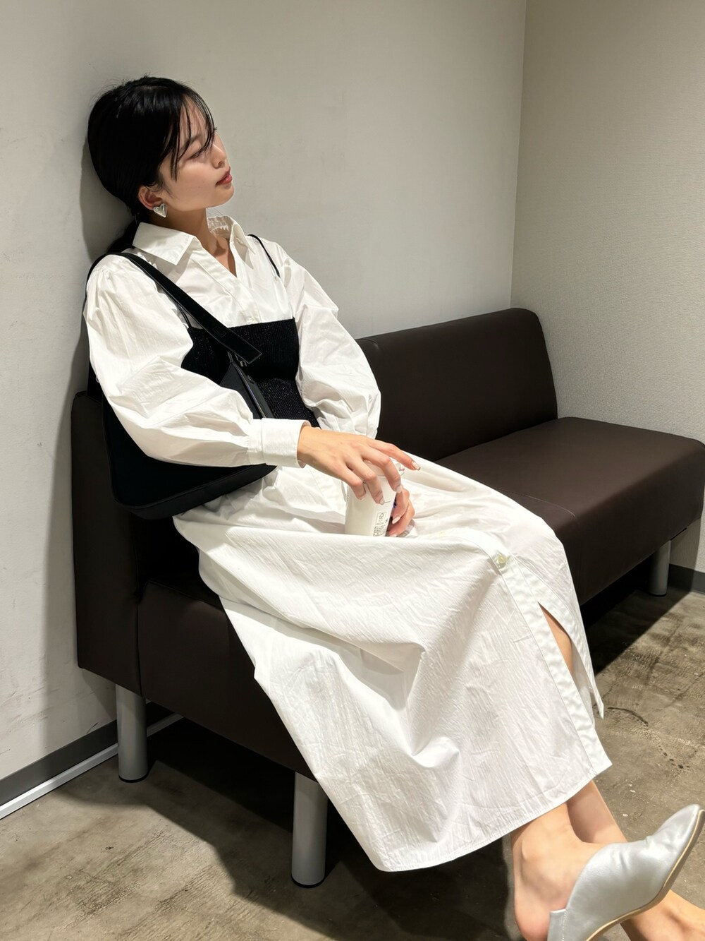 ホワイト系のシャツワンピース、シルバー系のパンプス、ブラック系のハンドバッグを着用したレディースの冬コーディネートの4枚目の写真