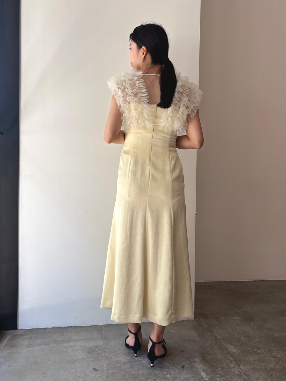 イエロー系のドレス、ブラック系のパンプスを着用したレディースの夏コーディネートの2枚目の写真