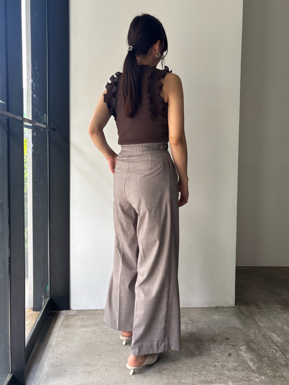 ブラウン系のニット/セーター、ベージュ系のその他パンツ、ホワイト系のサンダルを着用したレディースの春コーディネートの6枚目の写真