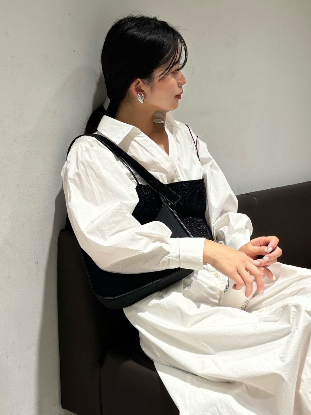 ホワイト系のシャツワンピース、シルバー系のパンプス、ブラック系のハンドバッグを着用したレディースの冬コーディネートの5枚目の写真