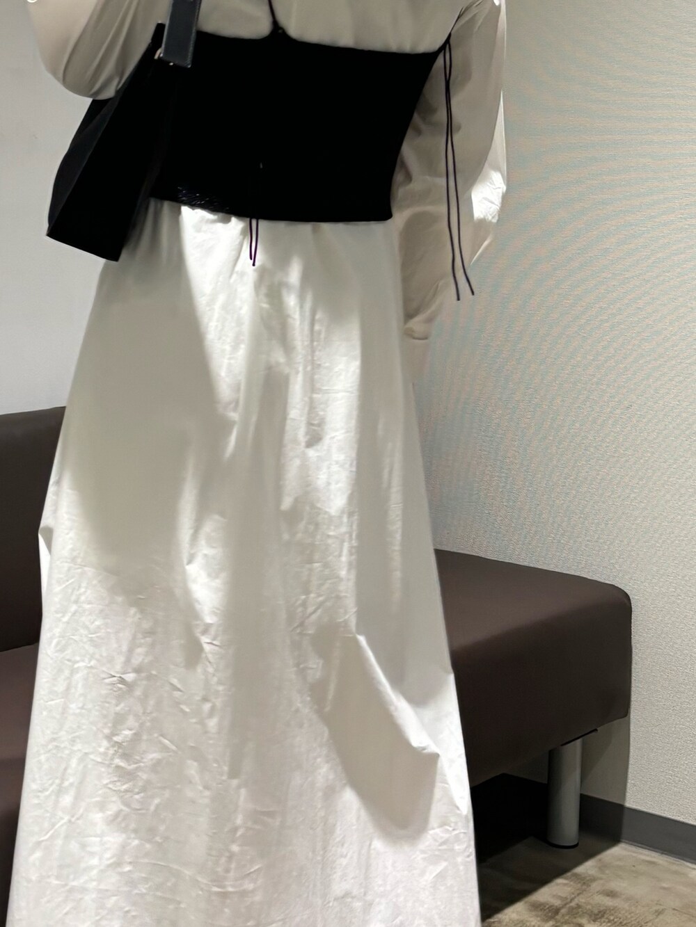 ホワイト系のシャツワンピース、シルバー系のパンプス、ブラック系のハンドバッグを着用したレディースの冬コーディネートの3枚目の写真