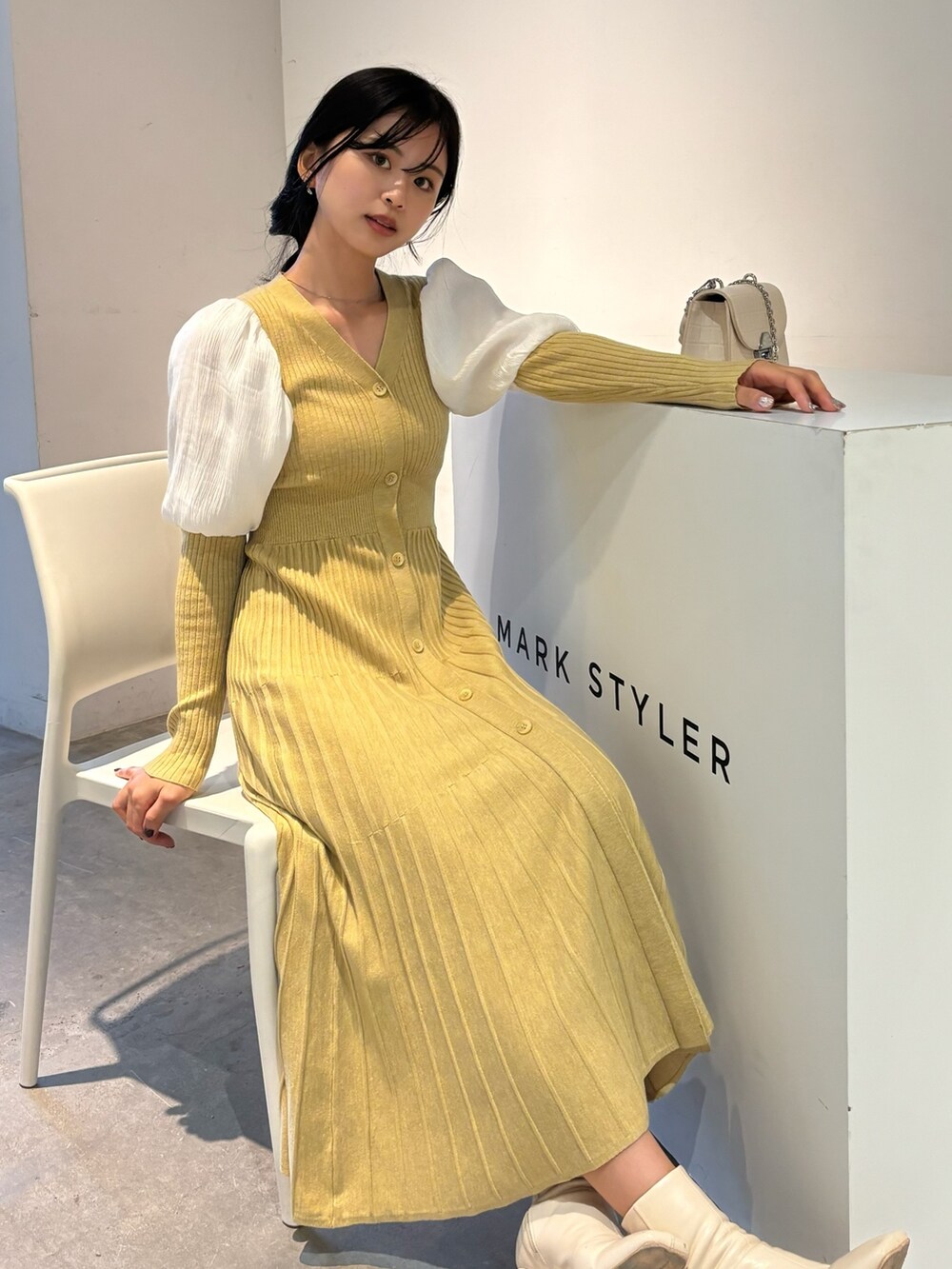 イエロー系のワンピース、ホワイト系のブーツを着用したレディースの冬コーディネートの5枚目の写真