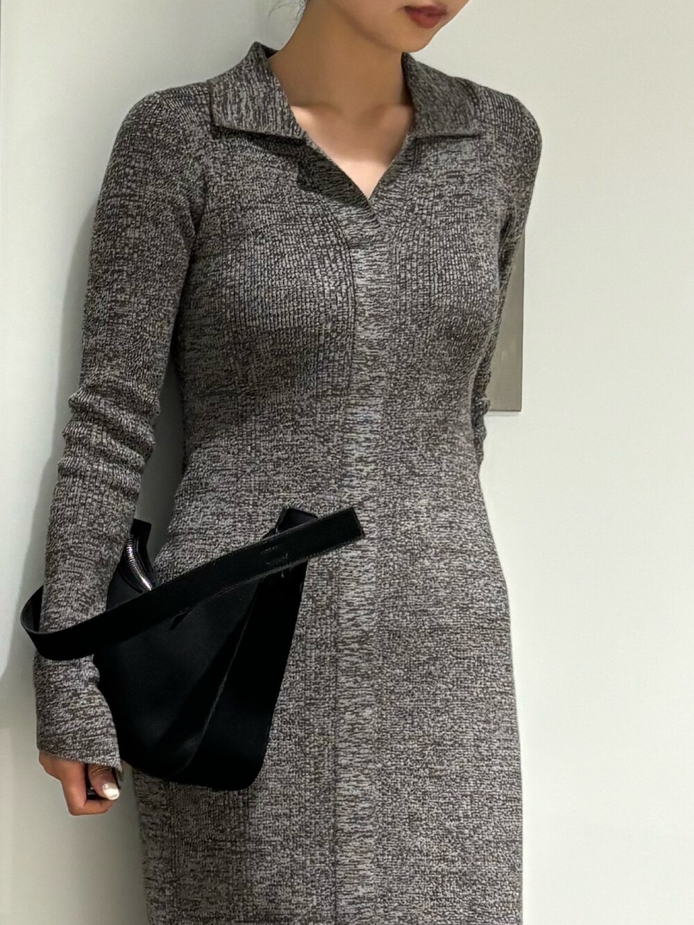 グレー系のワンピース、ブラック系のパンプス、ブラック系のハンドバッグを着用したレディースの冬コーディネートの2枚目の写真