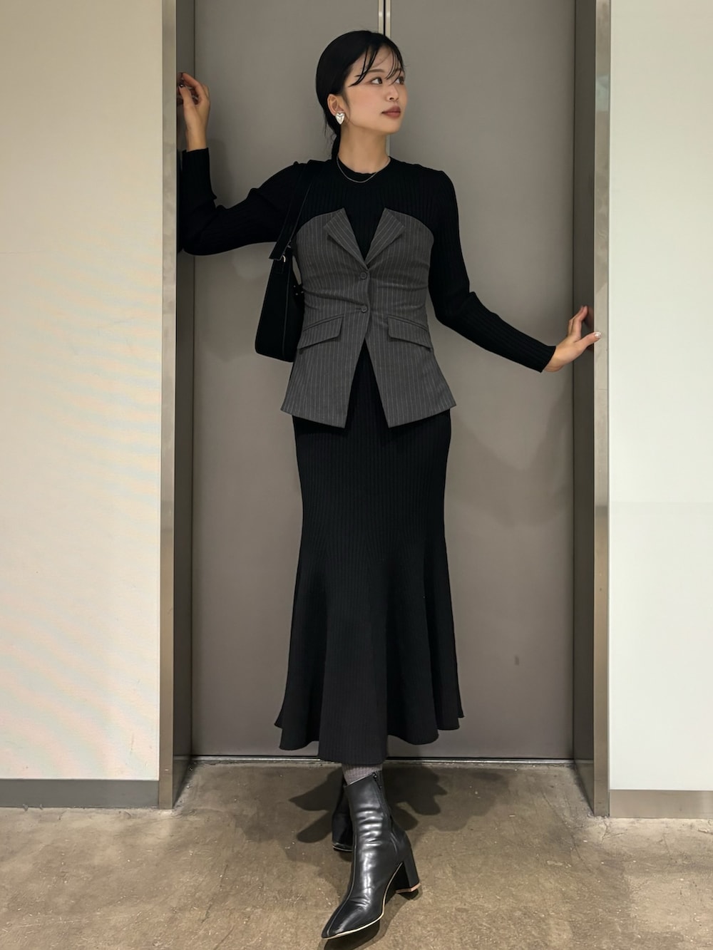 ブラック系のワンピース、ブラック系のハンドバッグ、ブラック系のブーツを着用したレディースの冬コーディネートの2枚目の写真