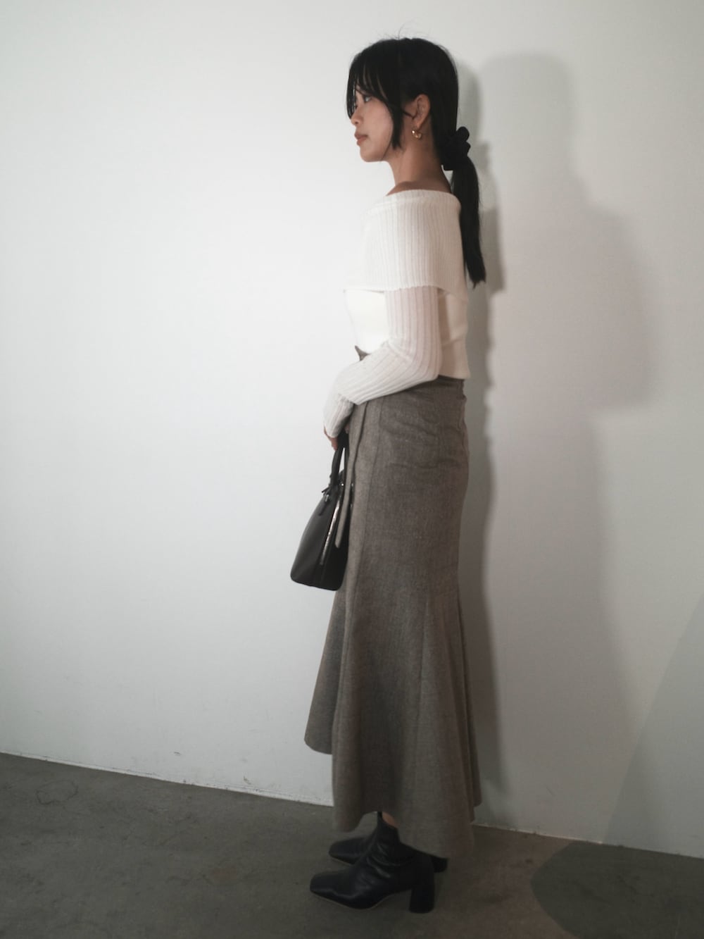 ホワイト系のニット/セーター、ブラウン系のスカート、ブラウン系のボストンバッグを着用したレディースの秋コーディネートの2枚目の写真