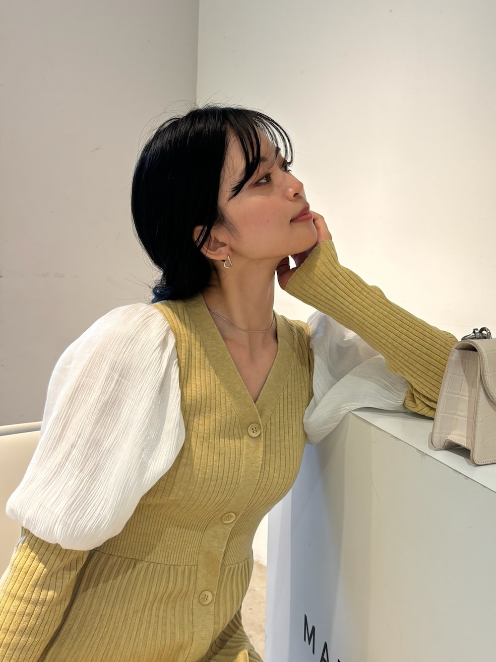 イエロー系のワンピース、ホワイト系のブーツを着用したレディースの冬コーディネートの4枚目の写真