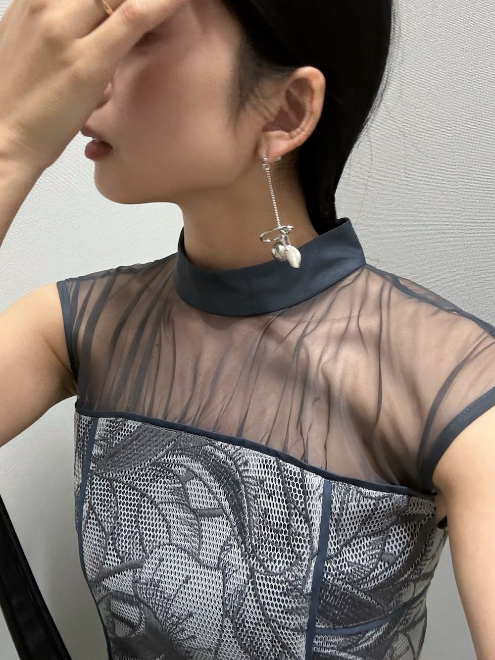 ブルー系のドレス、ブラック系のハンドバッグ、シルバー系のピアス（両耳用）を着用したレディースの春コーディネートの5枚目の写真