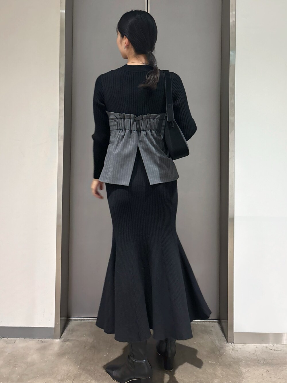 ブラック系のワンピース、ブラック系のハンドバッグ、ブラック系のブーツを着用したレディースの冬コーディネートの5枚目の写真