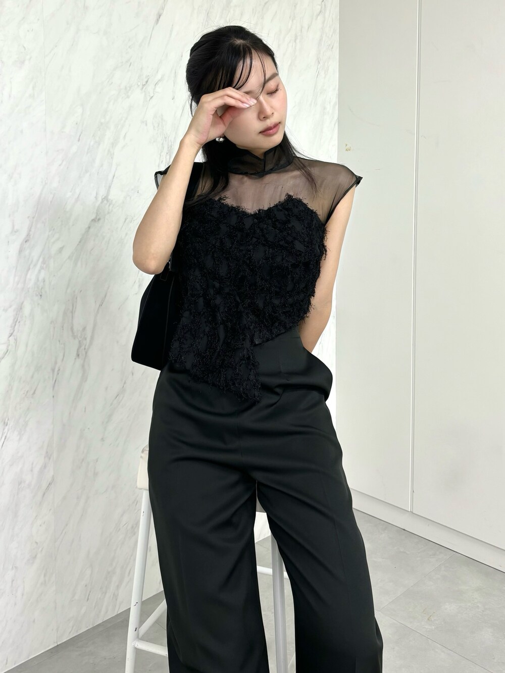 ブラック系のパンツドレス、ブラック系のハンドバッグ、シルバー系のパンプスを着用したレディースの冬コーディネートの3枚目の写真