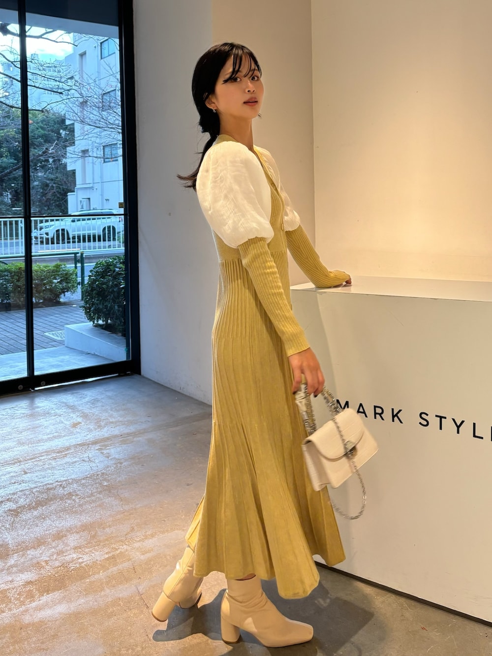 イエロー系のワンピース、ホワイト系のブーツを着用したレディースの冬コーディネートの2枚目の写真