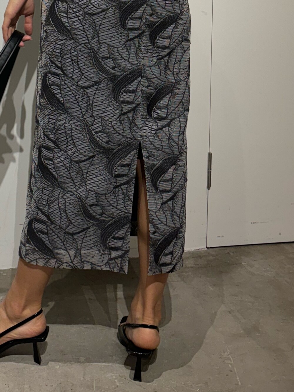 ブルー系のドレス、ブラック系のハンドバッグ、シルバー系のピアス（両耳用）を着用したレディースの春コーディネートの6枚目の写真