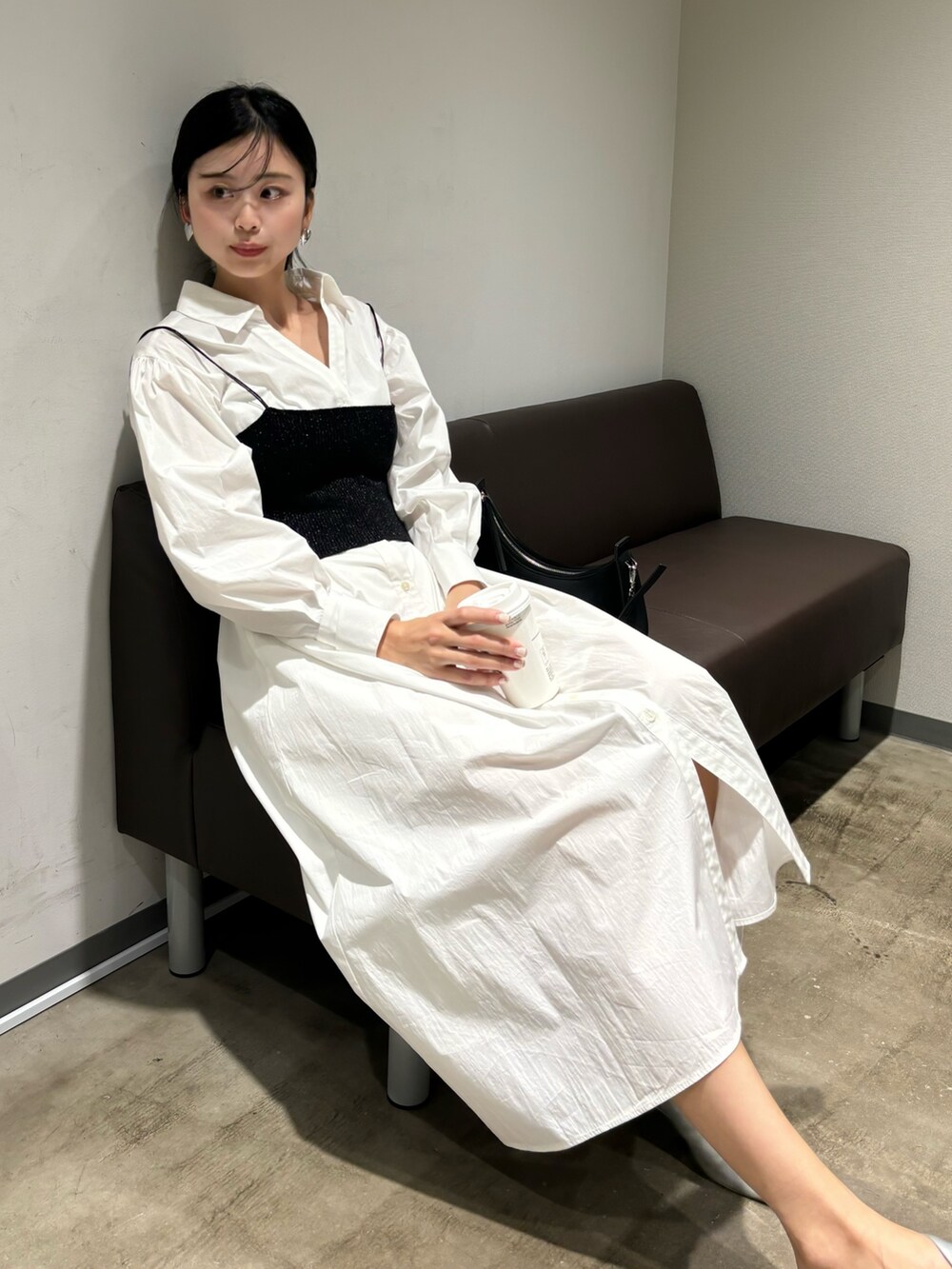 ホワイト系のシャツワンピース、シルバー系のパンプス、ブラック系のハンドバッグを着用したレディースの冬コーディネートの6枚目の写真