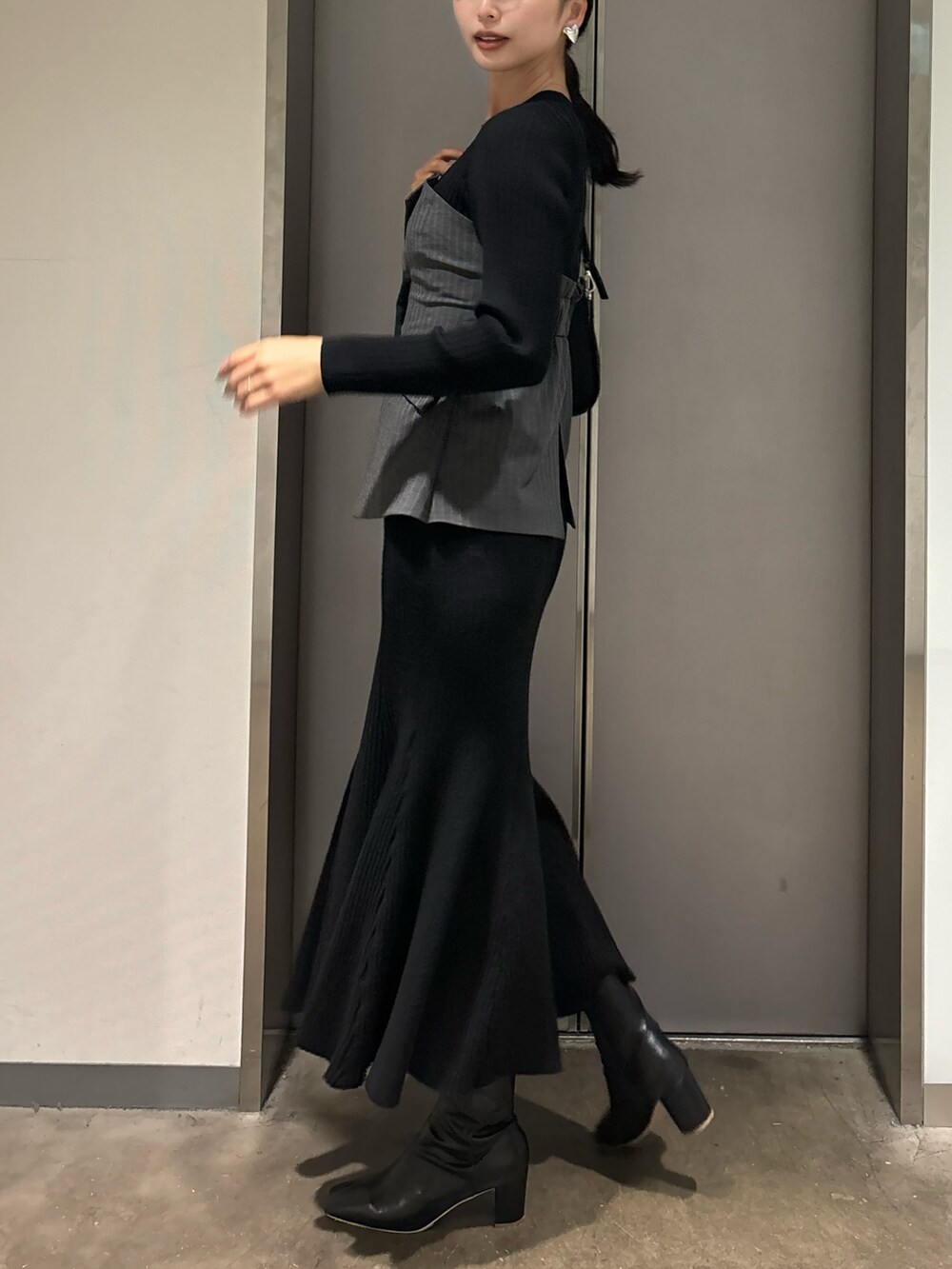 ブラック系のワンピース、ブラック系のハンドバッグ、ブラック系のブーツを着用したレディースの冬コーディネートの3枚目の写真