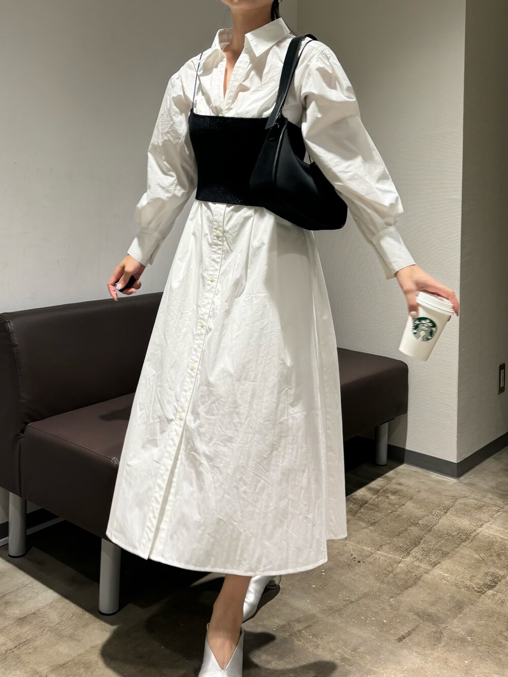 ホワイト系のシャツワンピース、シルバー系のパンプス、ブラック系のハンドバッグを着用したレディースの冬コーディネートの2枚目の写真