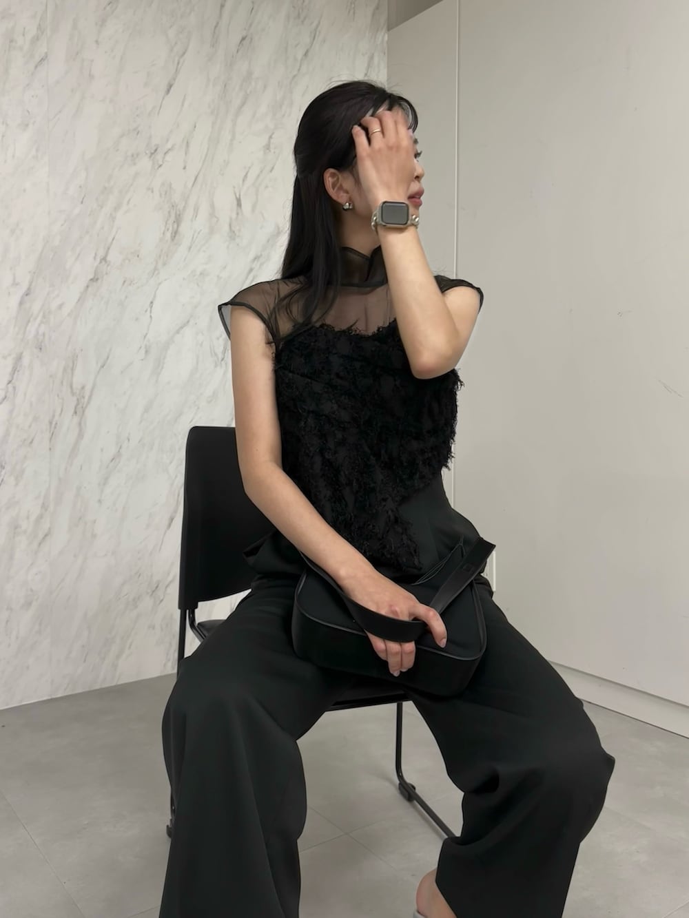 ブラック系のパンツドレス、ブラック系のハンドバッグ、シルバー系のパンプスを着用したレディースの冬コーディネートの4枚目の写真