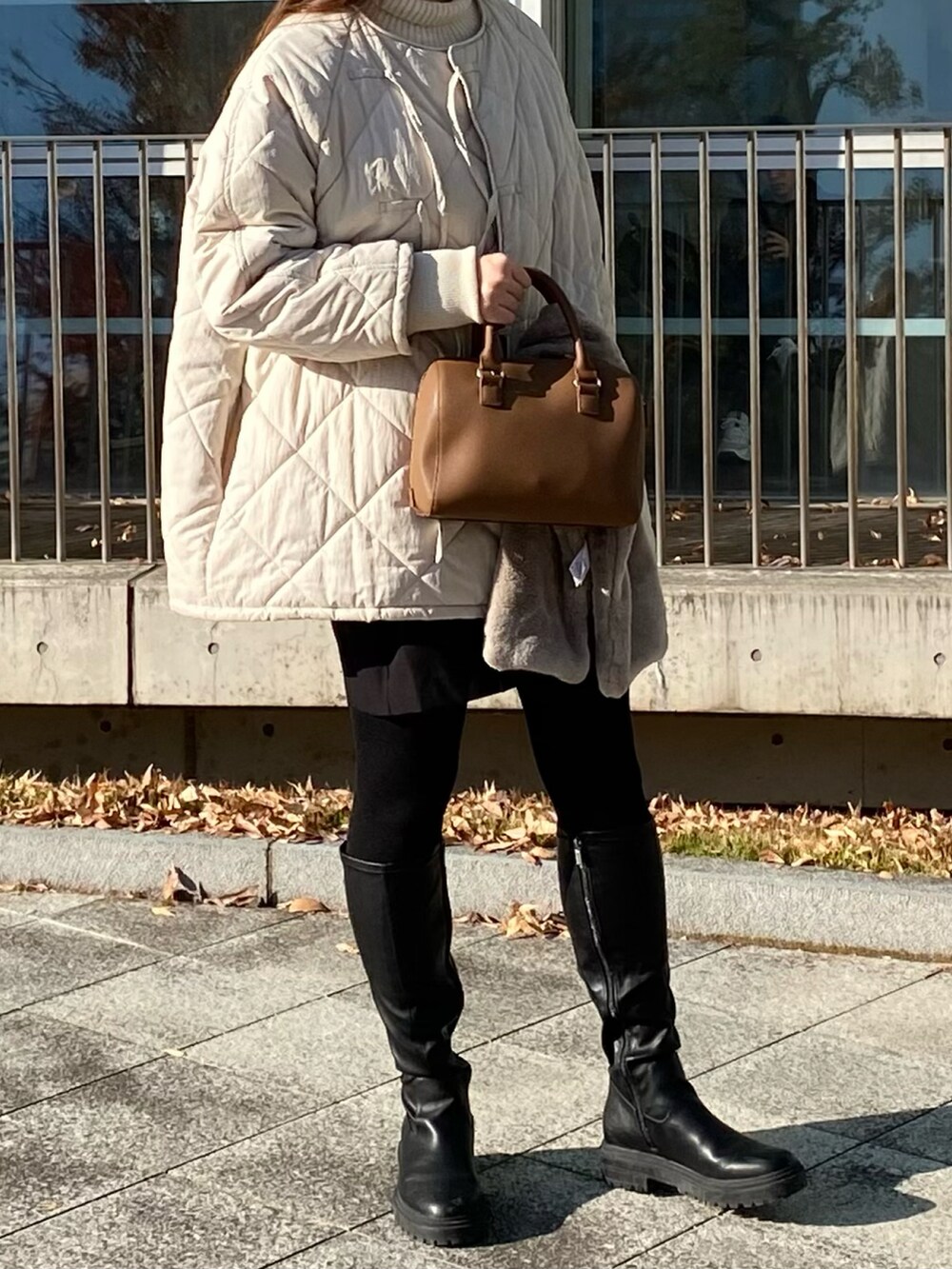 ブラウン系のボストンバッグ、ホワイト系のジャケット/アウター、ブラック系のパンツを着用したレディースの冬コーディネートの3枚目の写真