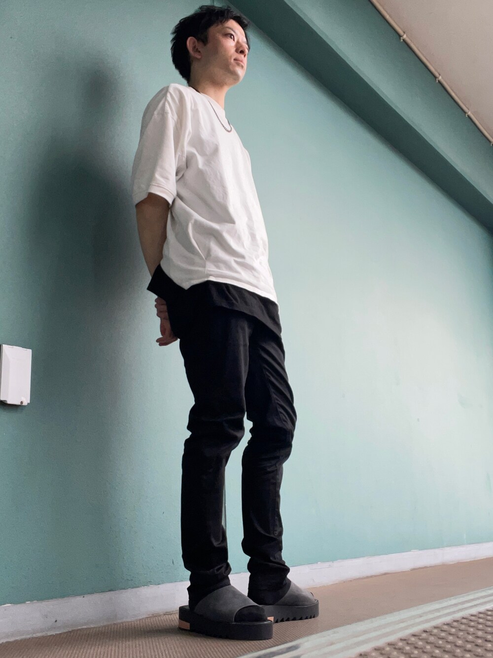 ホワイト系のTシャツ/カットソー、ブラック系のデニムパンツ、グレー系のサンダルを着用したメンズの夏コーディネートの3枚目の写真