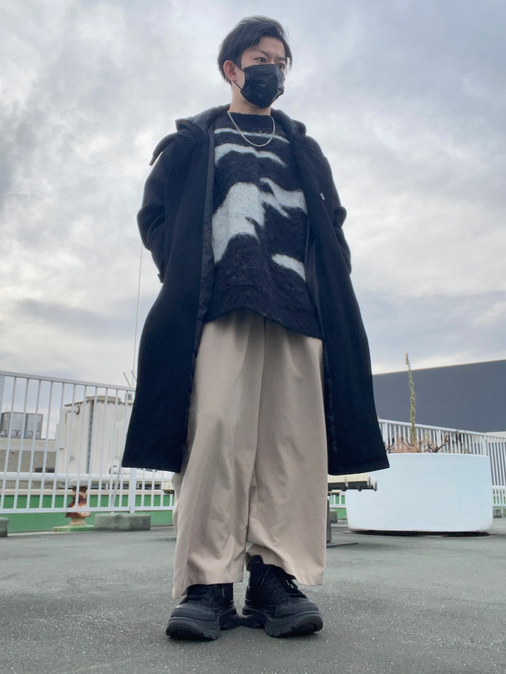 ブラック系のダッフルコート、ブラック系のニット/セーター、ホワイト系のその他パンツを着用したメンズの冬コーディネートの2枚目の写真