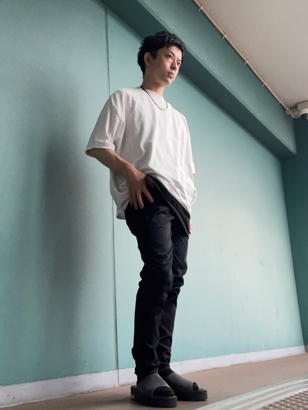 ホワイト系のTシャツ/カットソー、ブラック系のデニムパンツ、グレー系のサンダルを着用したメンズの夏コーディネートの2枚目の写真