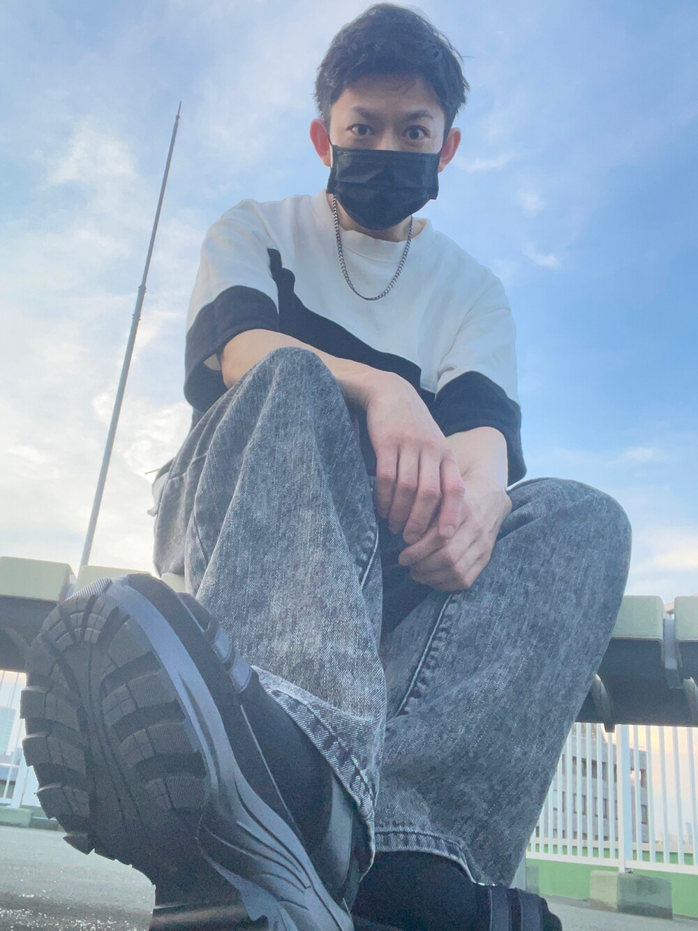 ホワイト系のトップス、ブラック系のデニムパンツ、ブラック系のサンダルを着用したメンズの夏コーディネートの4枚目の写真