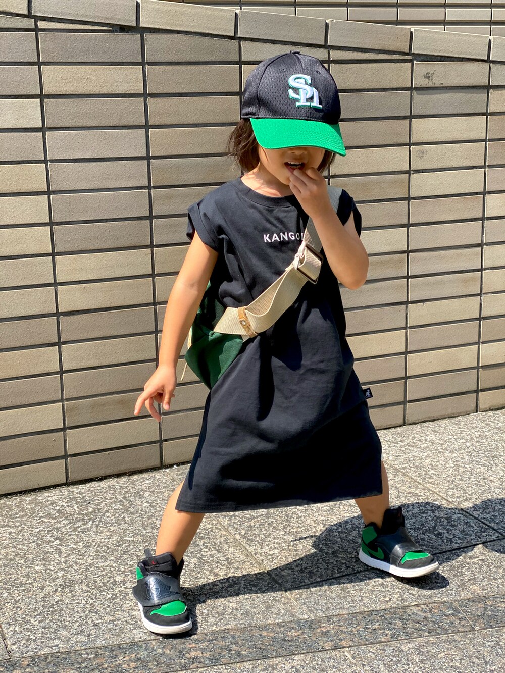 ブラック系のワンピース、グリーン系のボディバッグ/ウエストポーチ、グリーン系のスニーカーを着用したキッズの秋コーディネートの4枚目の写真