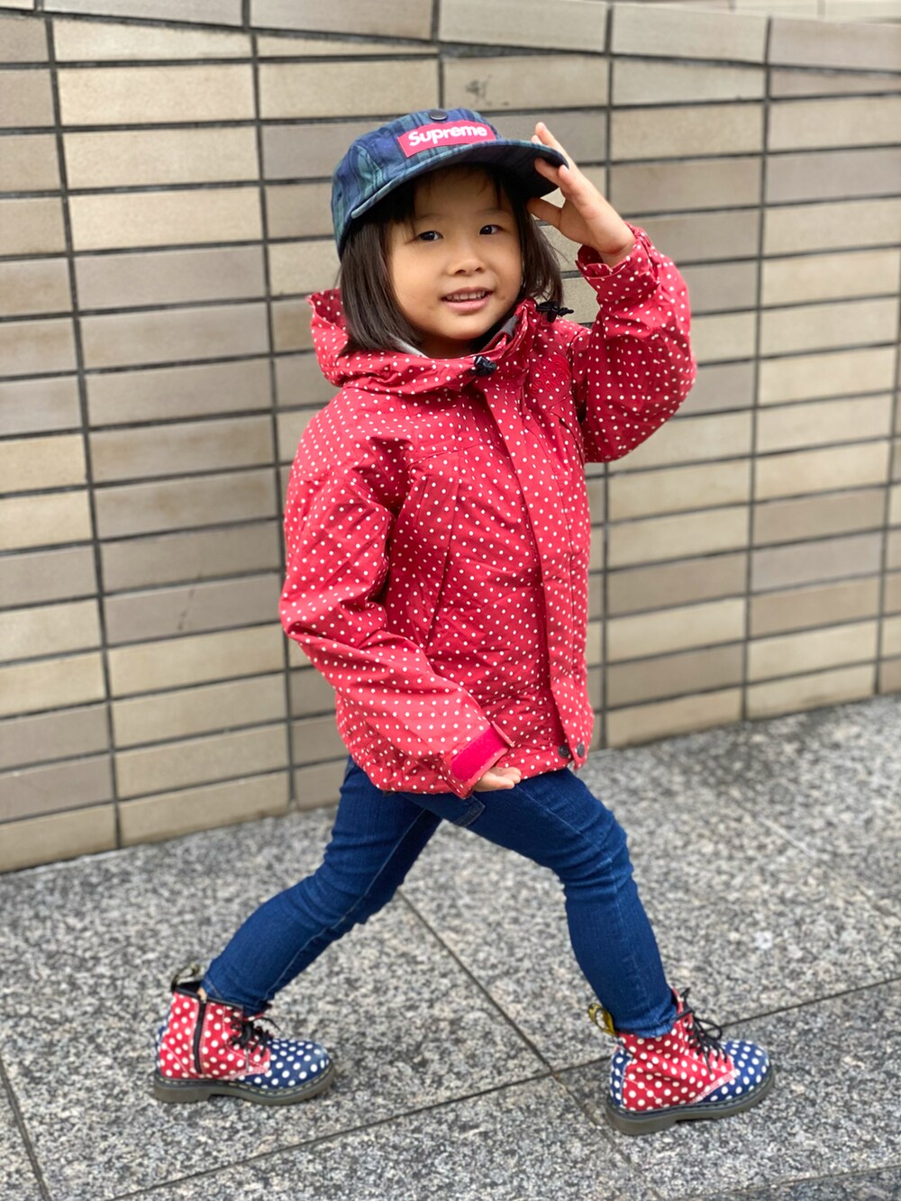 レッド系のナイロンジャケット、その他のブーツ、ブルー系のデニムパンツを着用したキッズの秋コーディネートの4枚目の写真