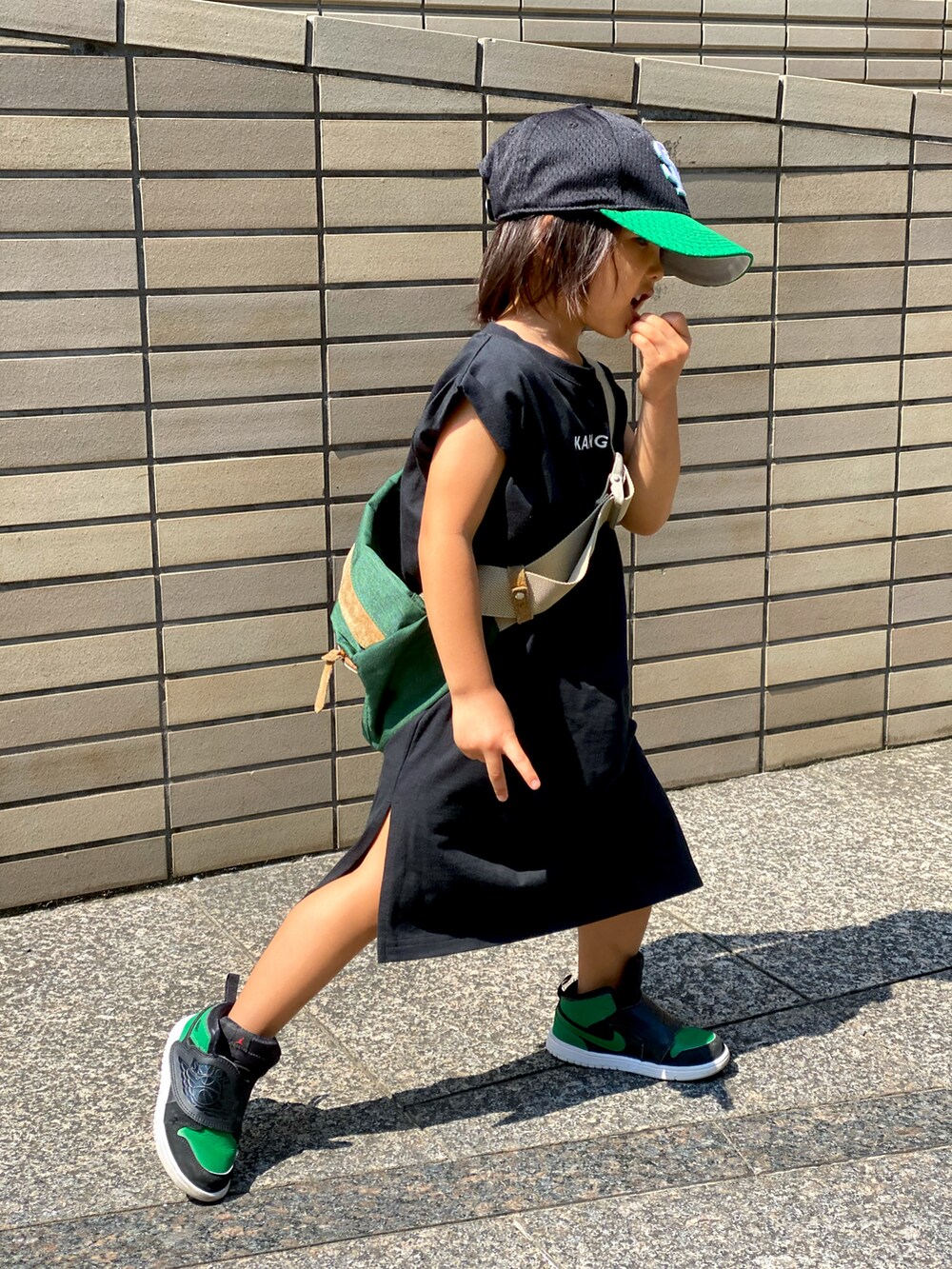 ブラック系のワンピース、グリーン系のボディバッグ/ウエストポーチ、グリーン系のスニーカーを着用したキッズの秋コーディネートの3枚目の写真