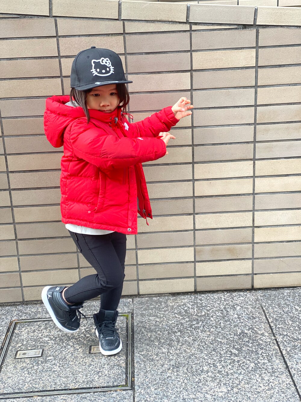 レッド系のダウンジャケット/コート、ホワイト系のTシャツ/カットソー、ブラック系のその他パンツを着用したキッズの冬コーディネートの4枚目の写真